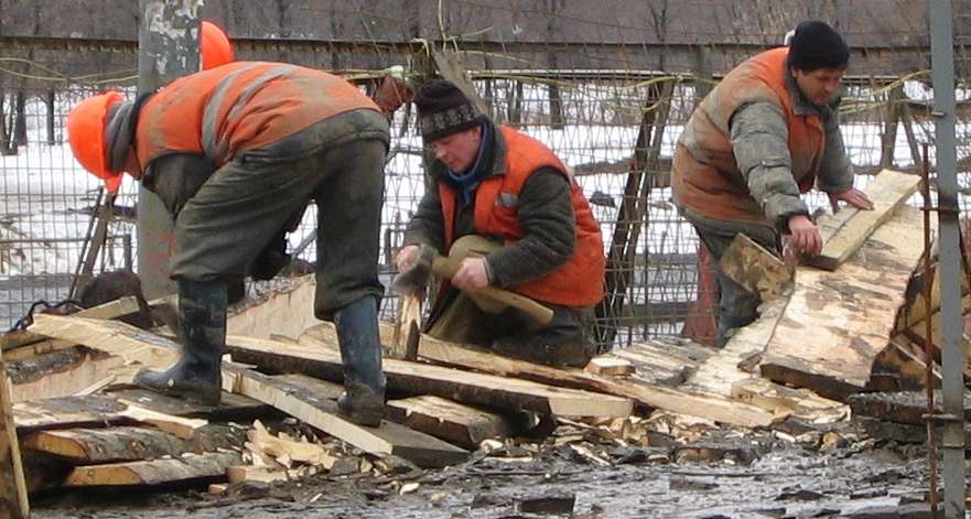 Выпиливание доски для установки между забуренными заранее трубами - традиционный способ укреплений грунта в России